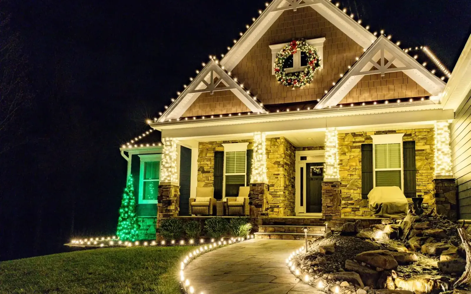 Warm white Christmas lights installed along a Seattle-area home's roofline, columns, and walkway